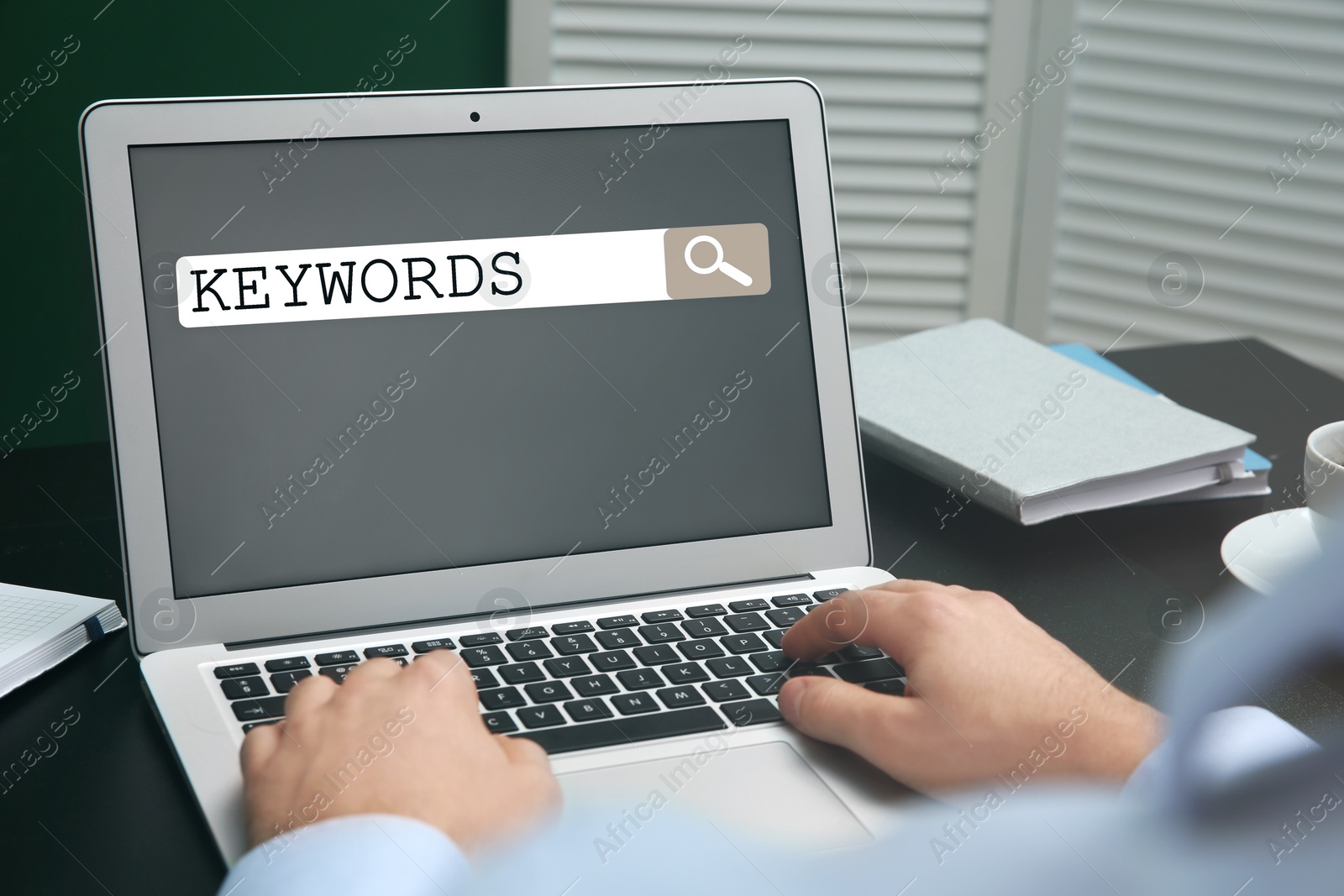 Image of Man with laptop searching for keywords at table, closeup