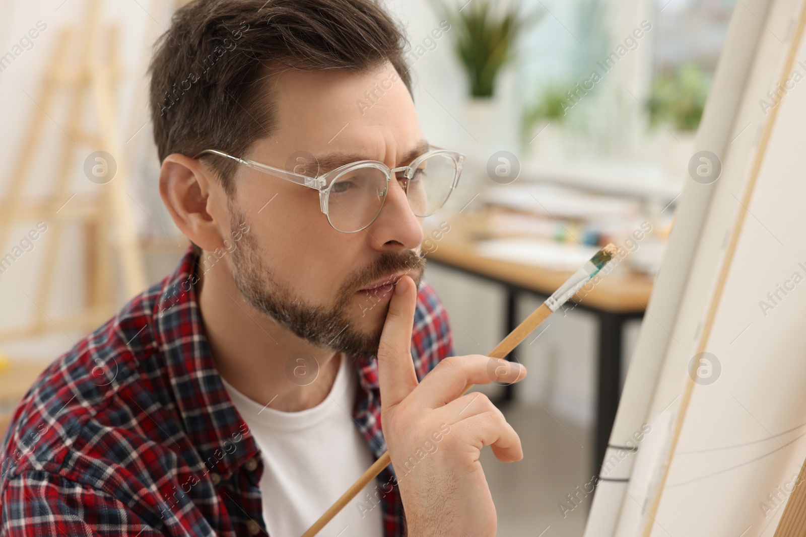 Photo of Man painting on canvas in studio. Creative hobby