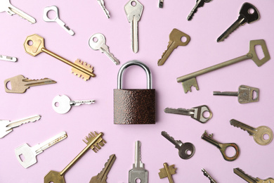 Photo of Steel padlock and keys on pink background, flat lay. Safety concept