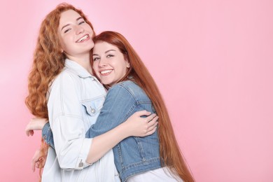 Photo of Portrait of beautiful young redhead sisters on pink background. Space for text