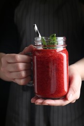 Photo of Woman holding tasty strawberry smoothie with mint on black background, closeup