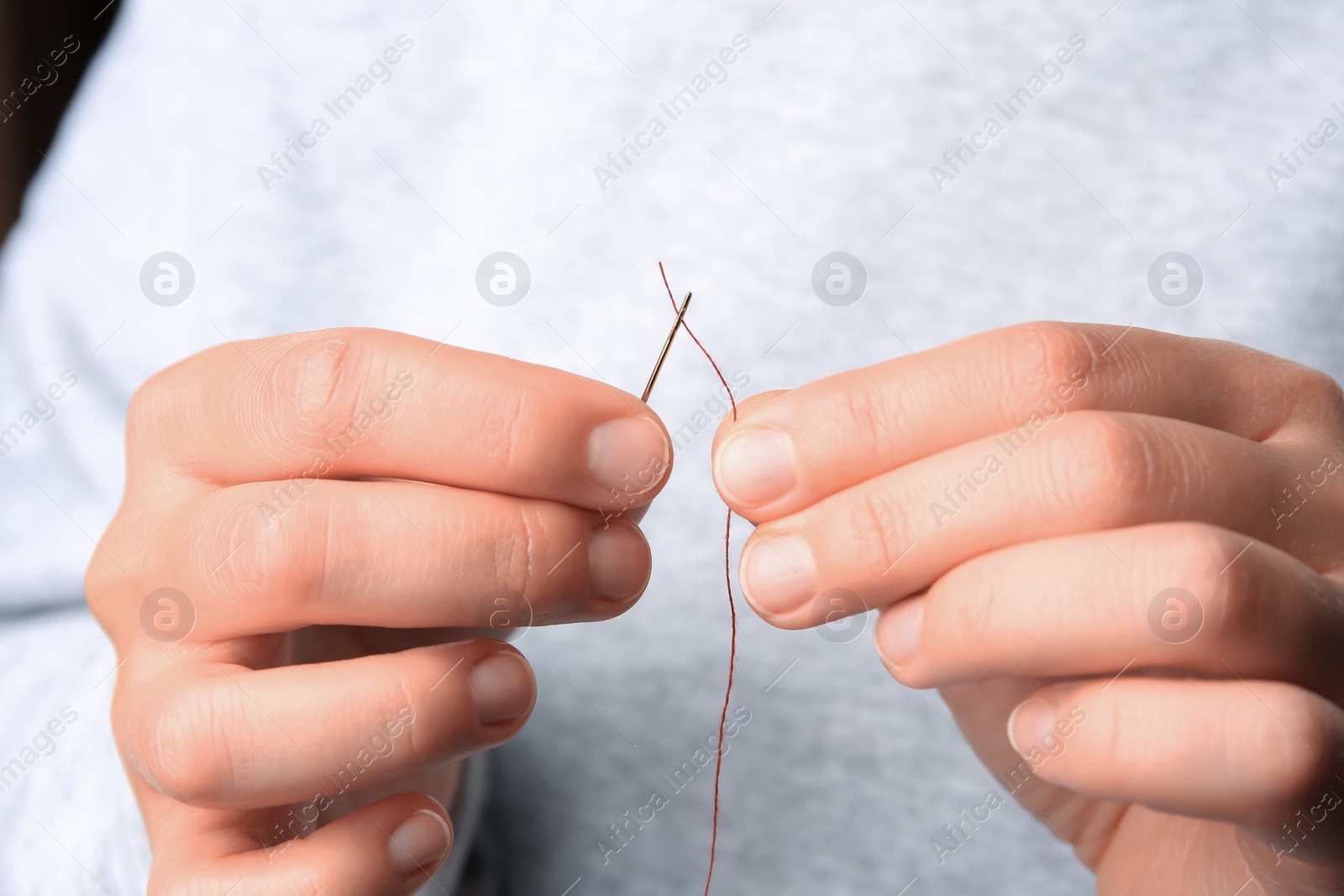 Photo of Closeup view of woman threading sewing needle