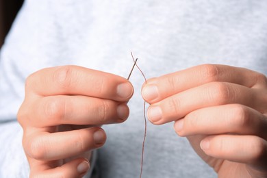 Closeup view of woman threading sewing needle