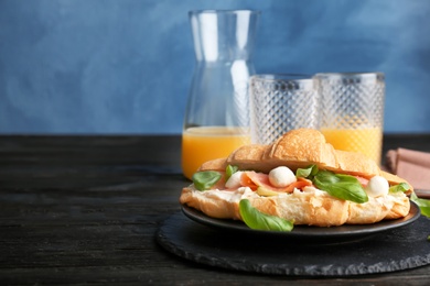 Photo of Tasty croissant sandwich with salmon on table