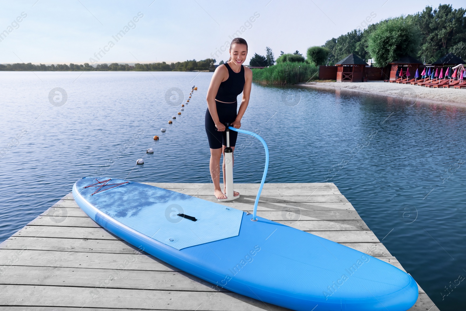 Photo of Woman pumping up SUP board on pier