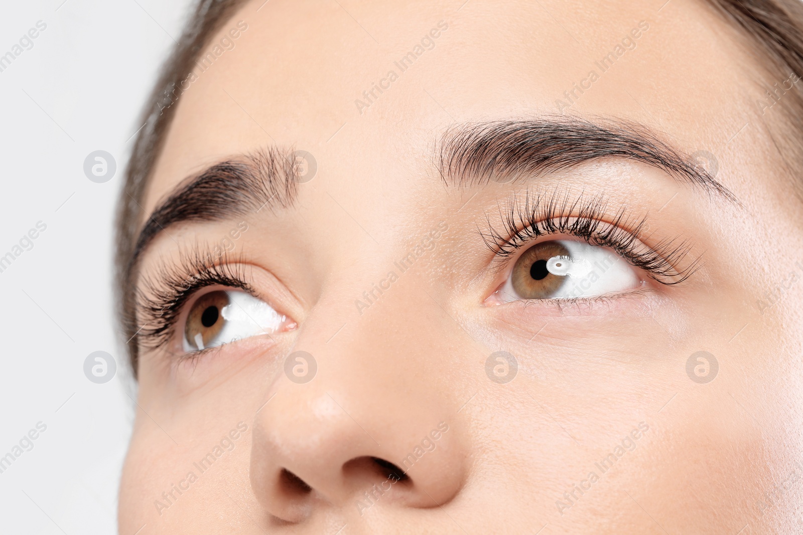 Photo of Young woman with beautiful eyelashes on light background, closeup view