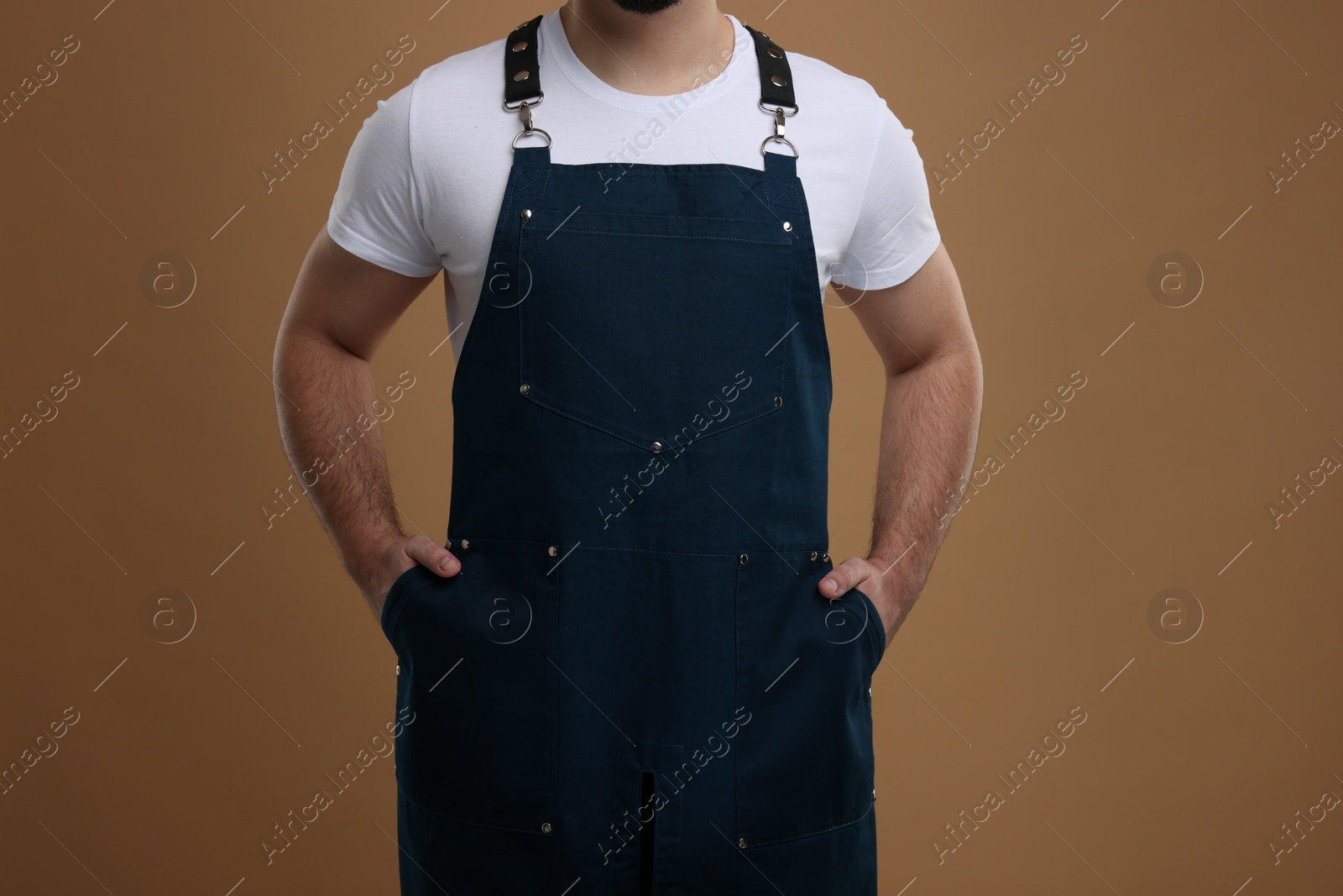 Photo of Man in kitchen apron on brown background, closeup. Mockup for design