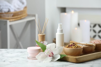 Beautiful composition with different spa products and orchid flower on white marble table indoors. Space for text