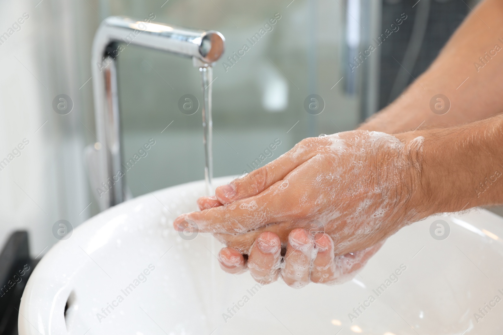 Photo of Man washing hands with soap over sink in bathroom, closeup