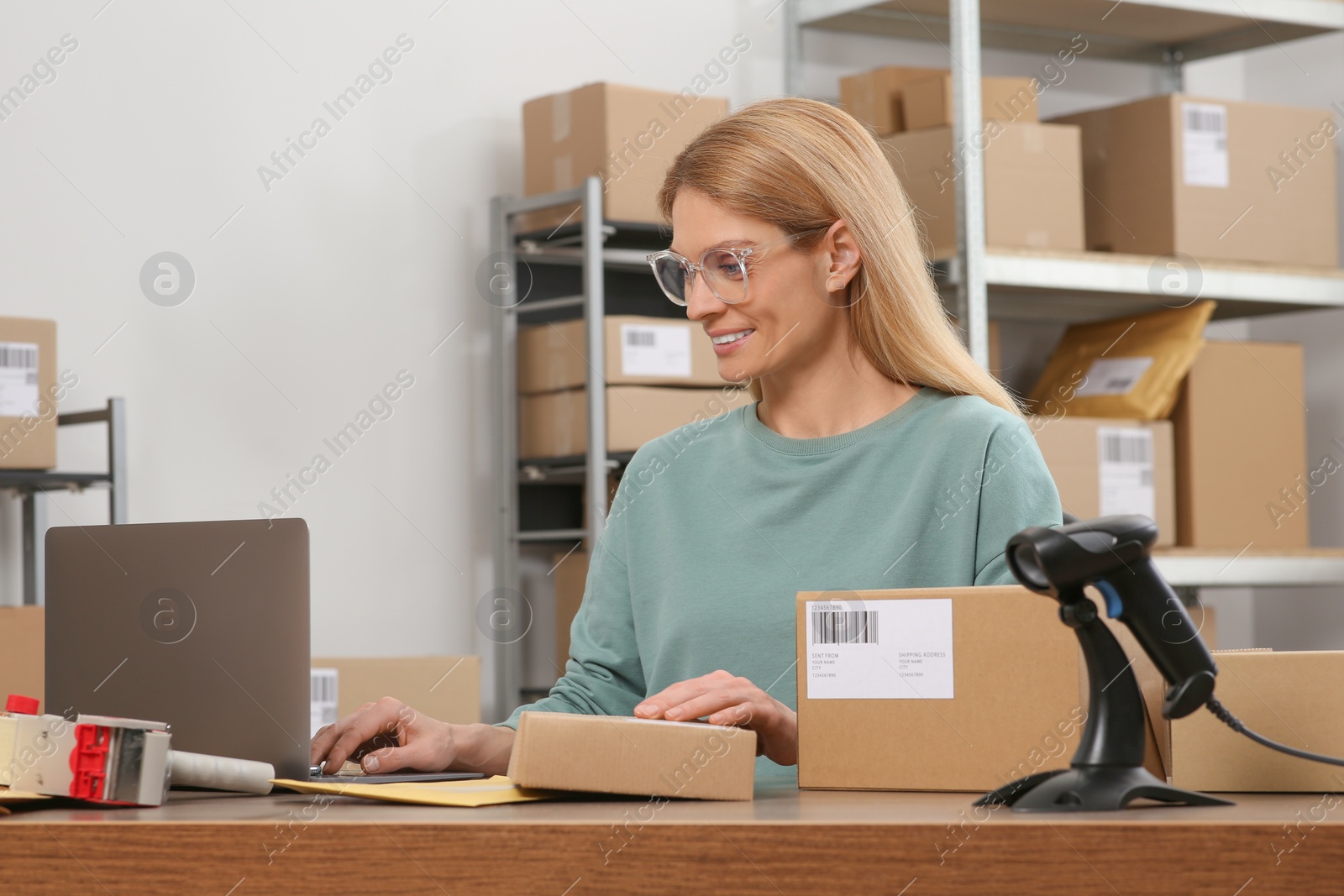 Photo of Seller with parcels and laptop in office. Online store