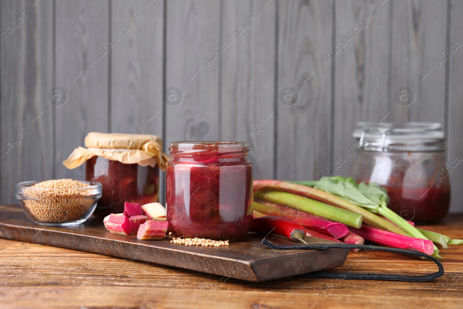 Photo of Tasty rhubarb sauce and ingredients on wooden table, space for text