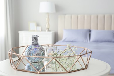 Stylish catalytic lamp with burning candle and gypsophila on table in bedroom. Cozy interior