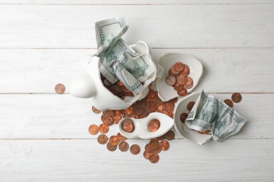 Broken piggy bank with coins and banknotes on wooden table, top view