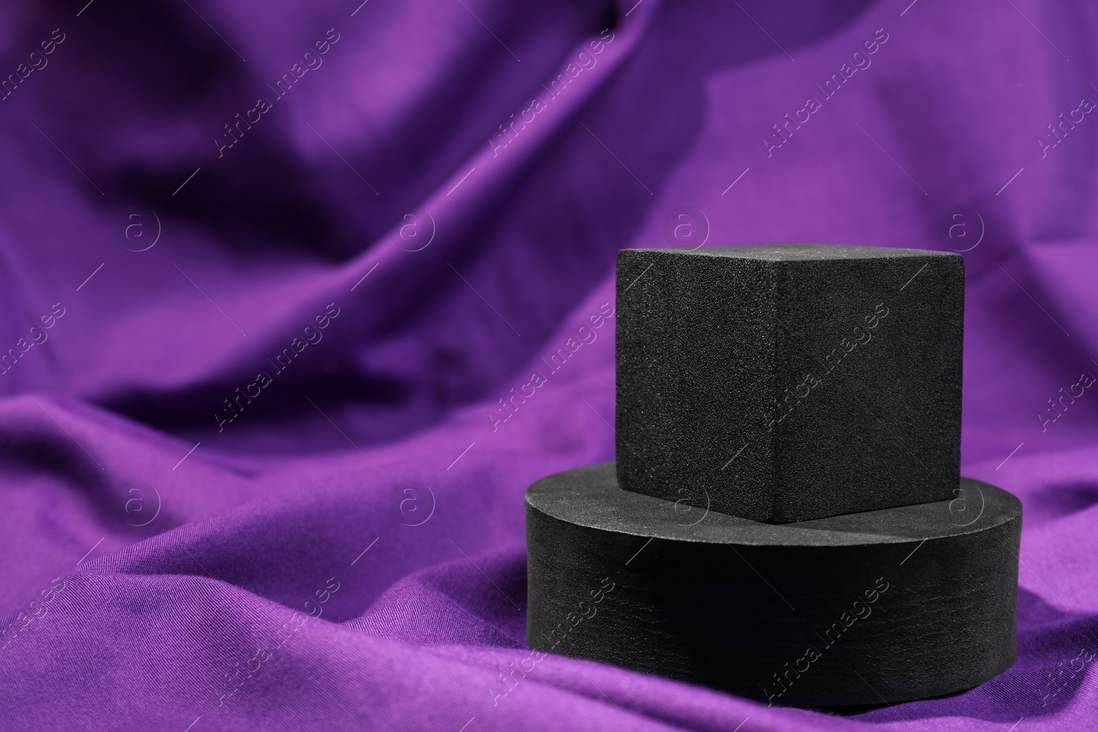 Photo of Black geometric figures on purple fabric, space for text. Stylish presentation for product