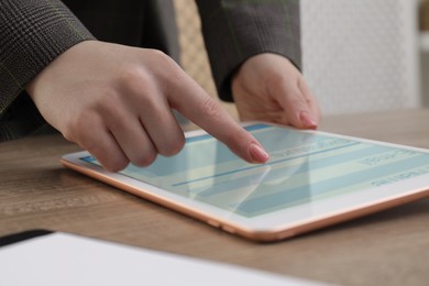 Electronic signature. Woman using tablet at wooden table, closeup