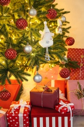 Pile of gift boxes near Christmas tree indoors