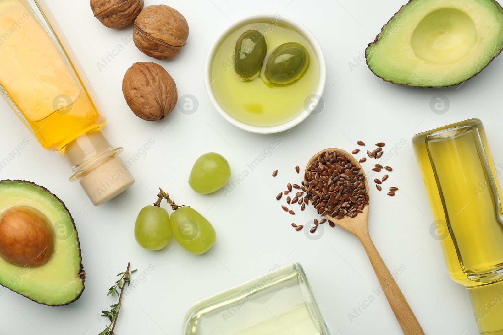 Photo of Vegetable fats. Different oils in glass bottles and ingredients on white table, flat lay