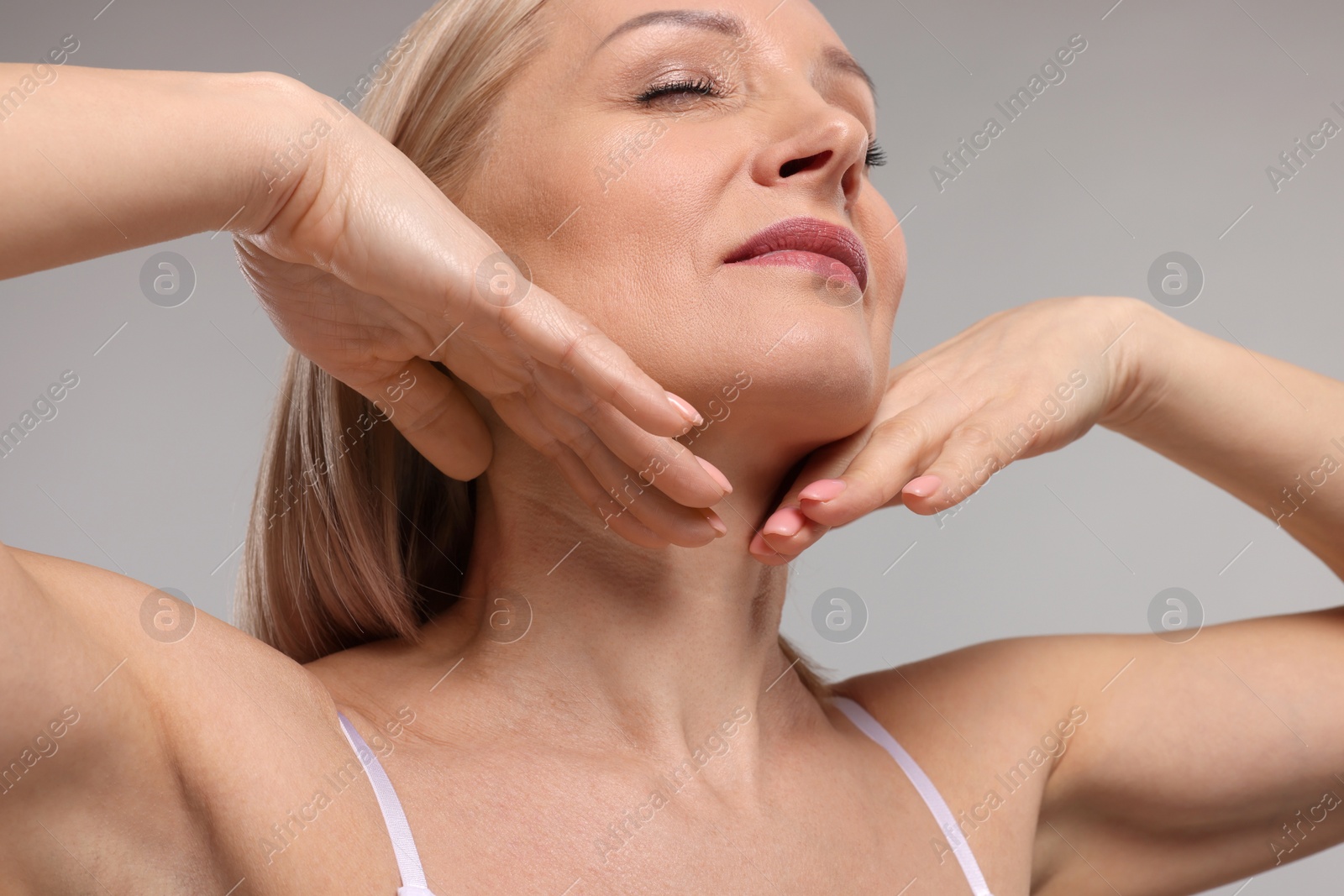 Photo of Beautiful woman touching her neck on grey background, closeup