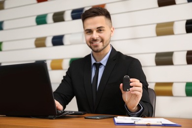 Photo of Salesman with car key at desk in office