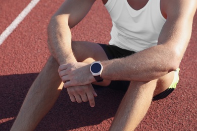 Photo of Man with fitness tracker after training at stadium, closeup