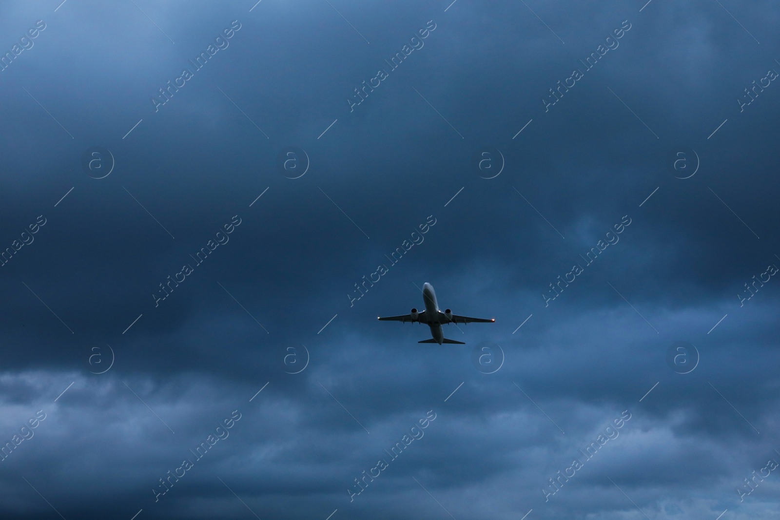 Photo of Modern white airplane flying in sky with clouds, low angle view