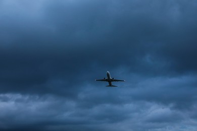Modern white airplane flying in sky with clouds, low angle view