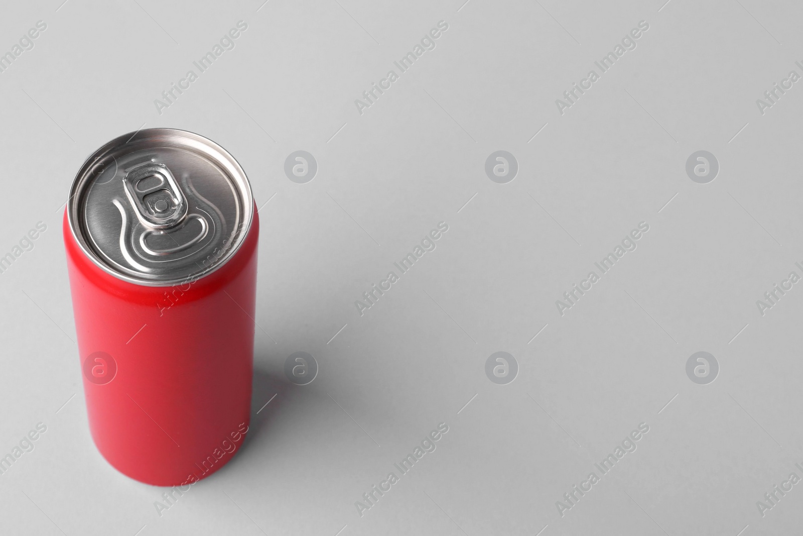 Photo of Energy drink in red can on light grey background, space for text