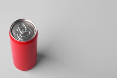 Photo of Energy drink in red can on light grey background, space for text