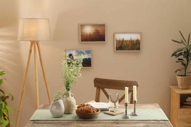 Photo of Clean tableware, candlesticks, flowers and fresh pastries on table in stylish dining room