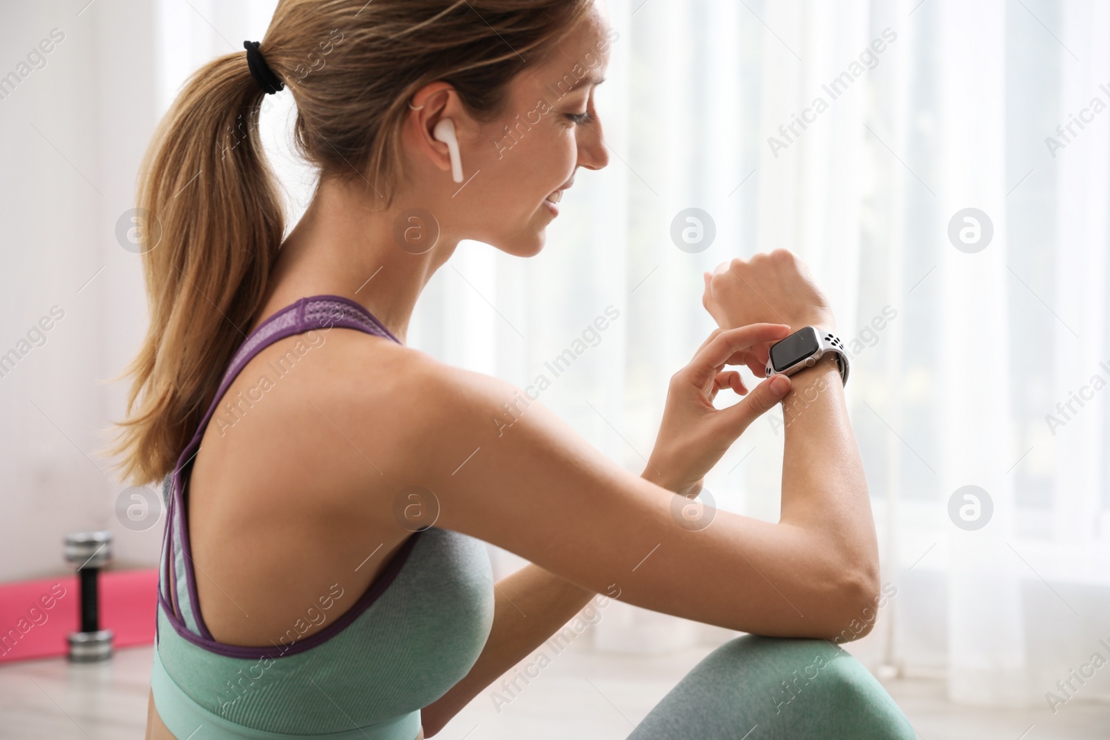 Photo of Young woman using smart watch during training indoors, closeup