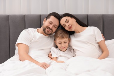 Photo of Pregnant woman with her son and husband in bed at home. Cute family