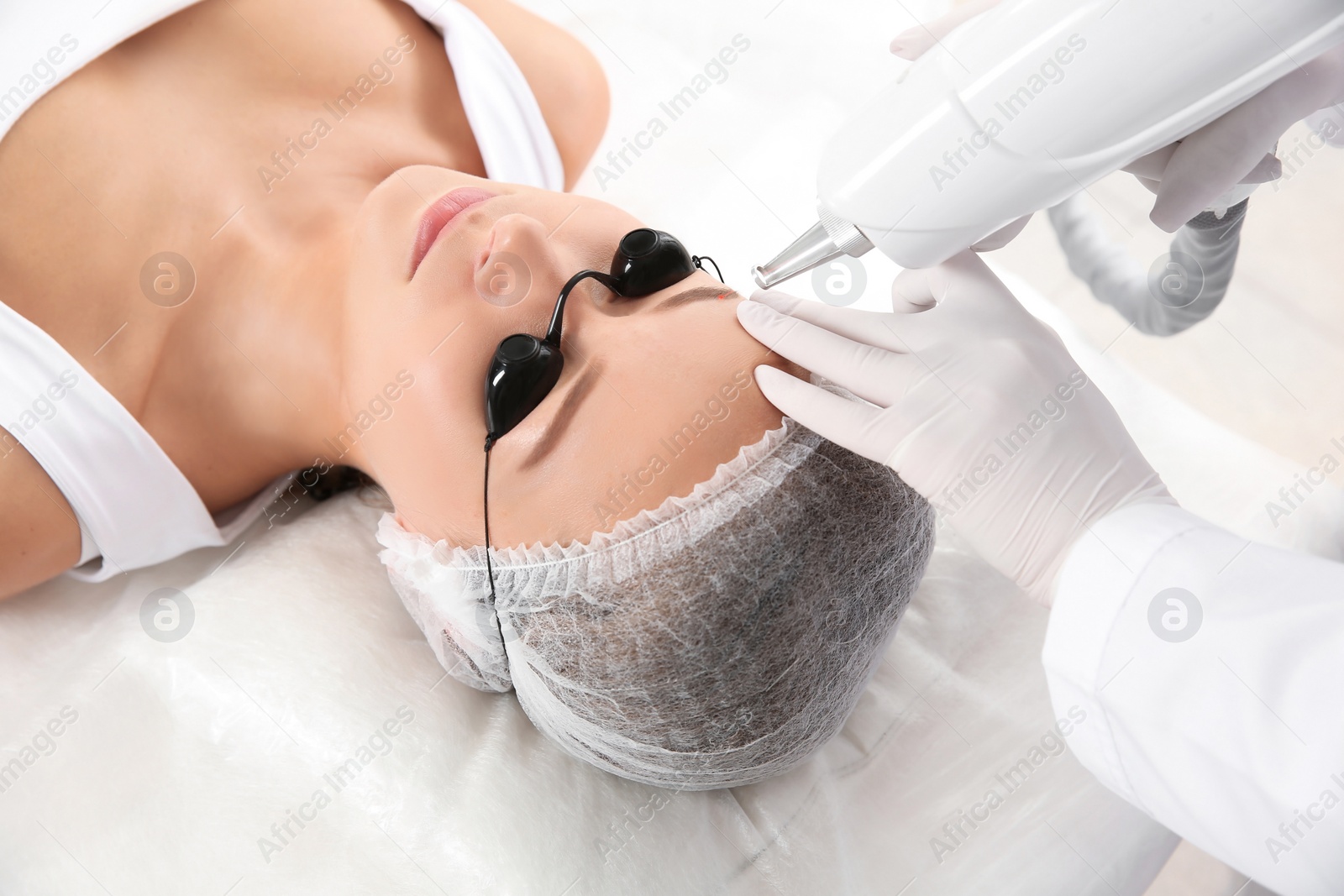 Photo of Young woman undergoing laser removal of permanent makeup in salon. Eyebrow correction