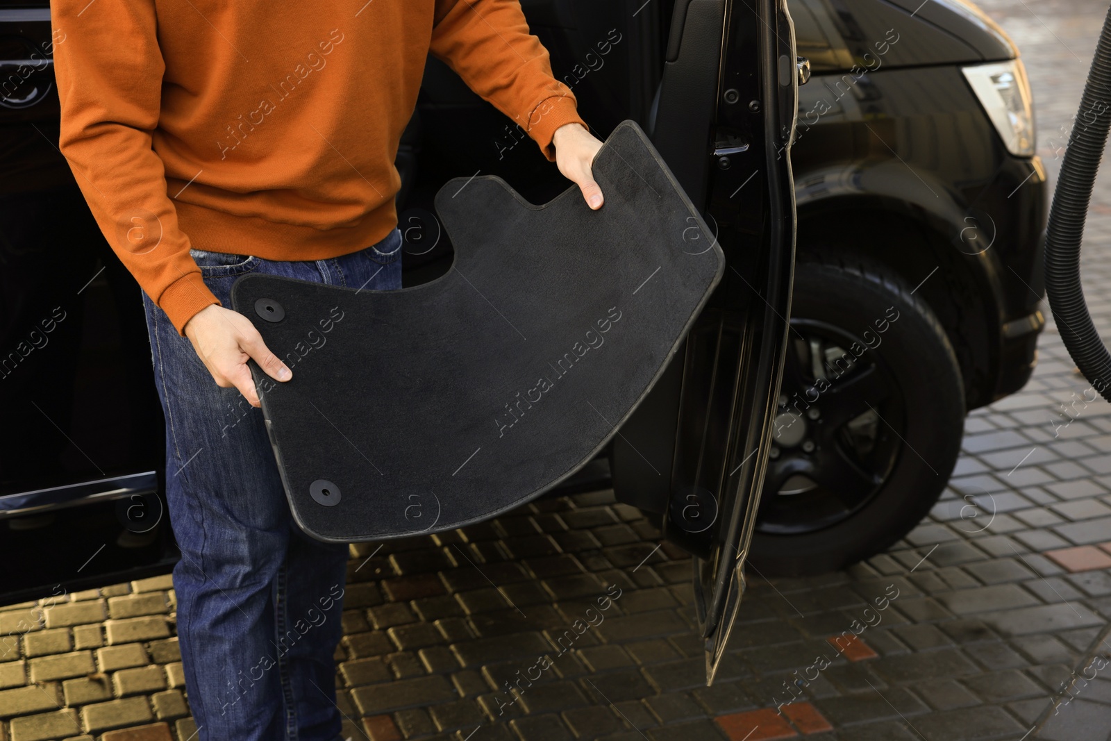 Photo of Man taking carpets from auto for cleaning at self-service car wash, closeup