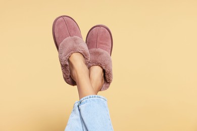 Photo of Woman in warm soft slippers on beige background, closeup. Space for text