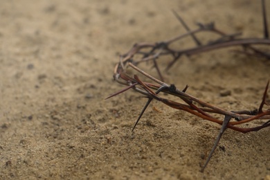 Photo of Crown of thorns on sand, closeup with space for text. Easter attribute