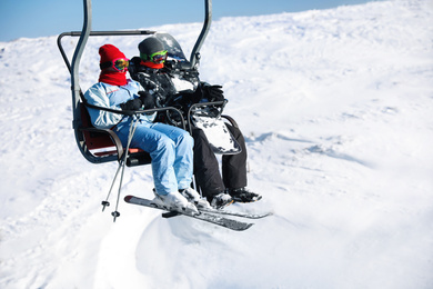 Photo of People using chairlift at mountain ski resort, space for text. Winter vacation