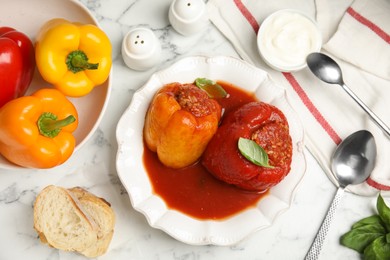 Photo of Delicious stuffed peppers served on white marble table, flat lay