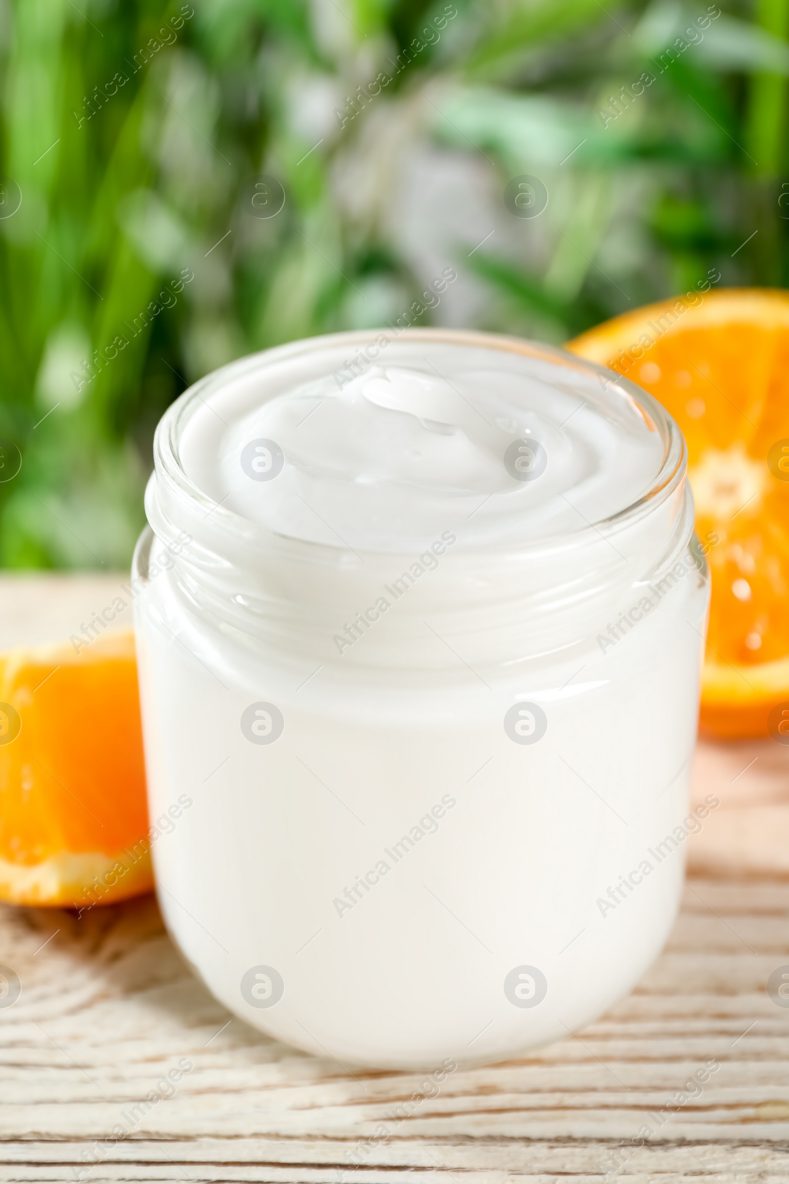 Photo of Jar of hand cream and orange on white wooden table, closeup