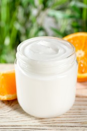Photo of Jar of hand cream and orange on white wooden table, closeup
