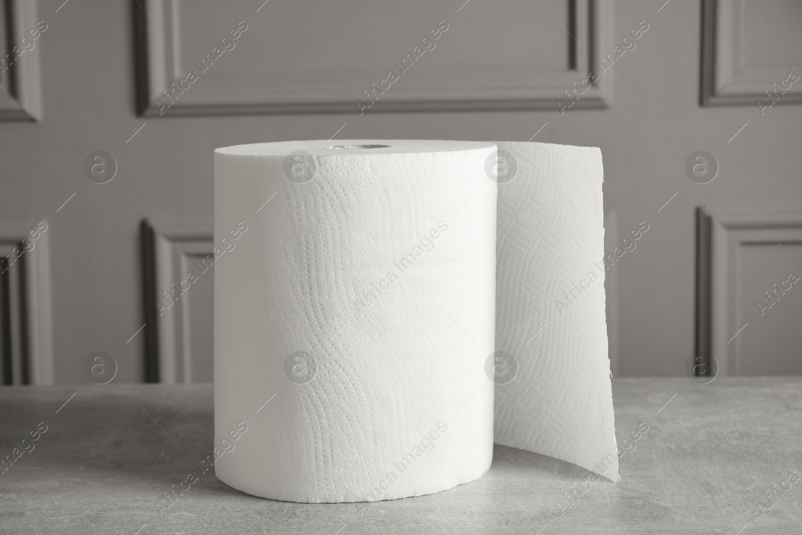 Photo of Roll of white paper towels on grey table