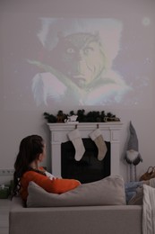 Photo of Lviv, Ukraine – January 24, 2023: Woman watching How the Grinch Stole Christmas movie via video projector at home