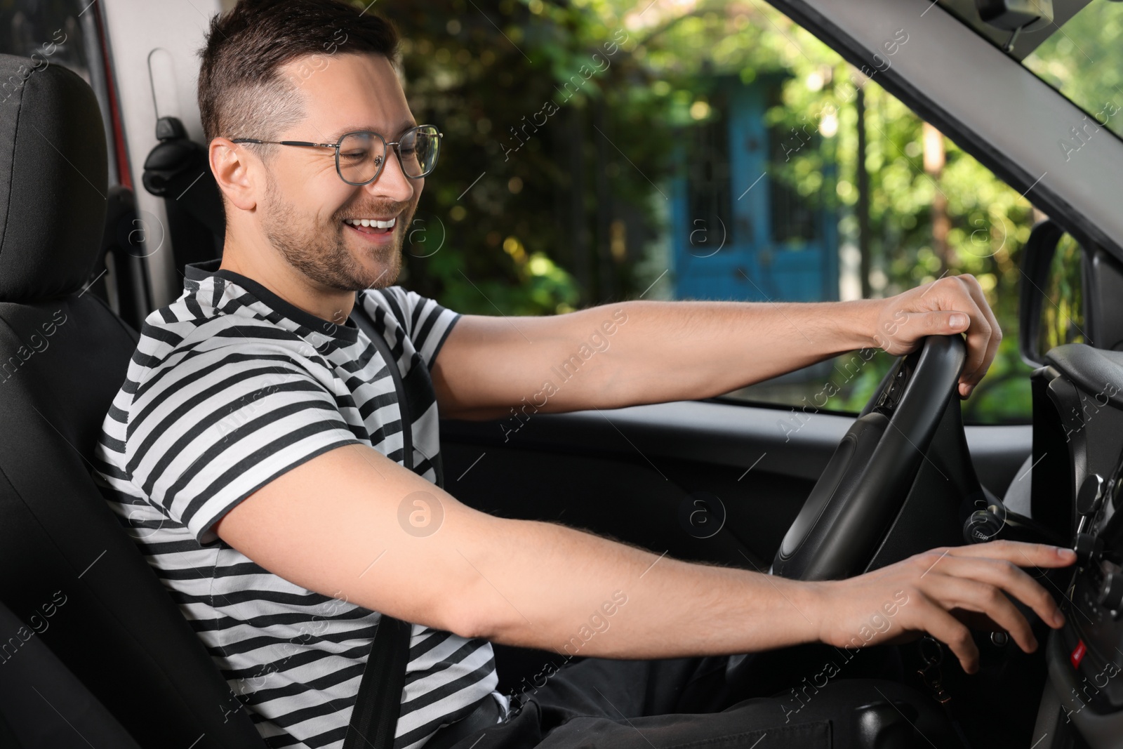 Photo of Listening to radio while driving. Handsome man turning volume button on vehicle audio in car