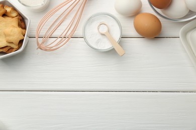 Flat lay composition with baking powder and products on white wooden table. Space for text