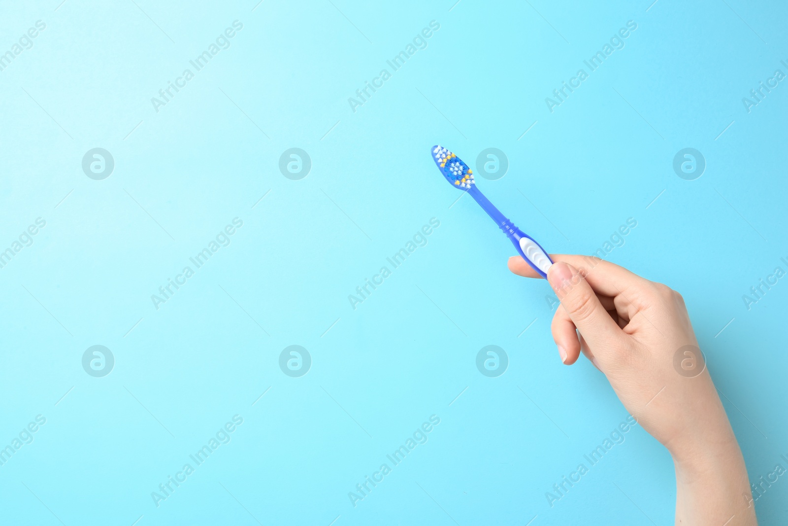 Photo of Woman holding manual toothbrush against color background