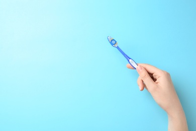 Photo of Woman holding manual toothbrush against color background