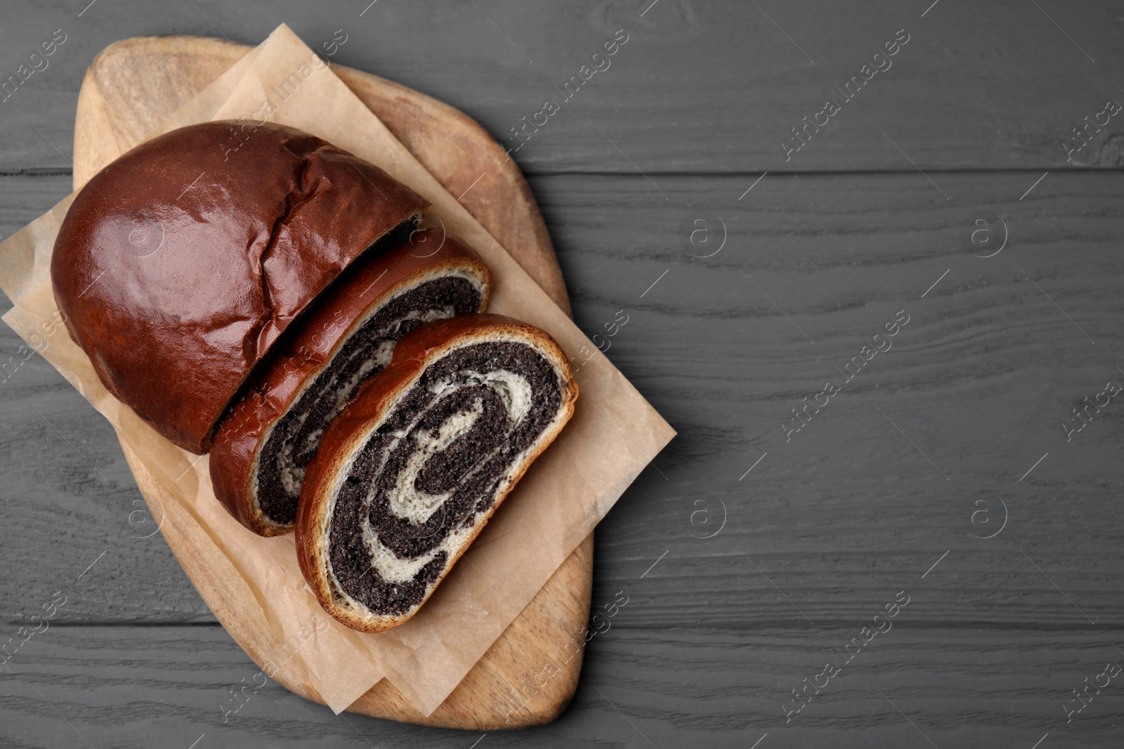 Photo of Cut poppy seed roll on grey wooden table, top view with space for text. Tasty cake