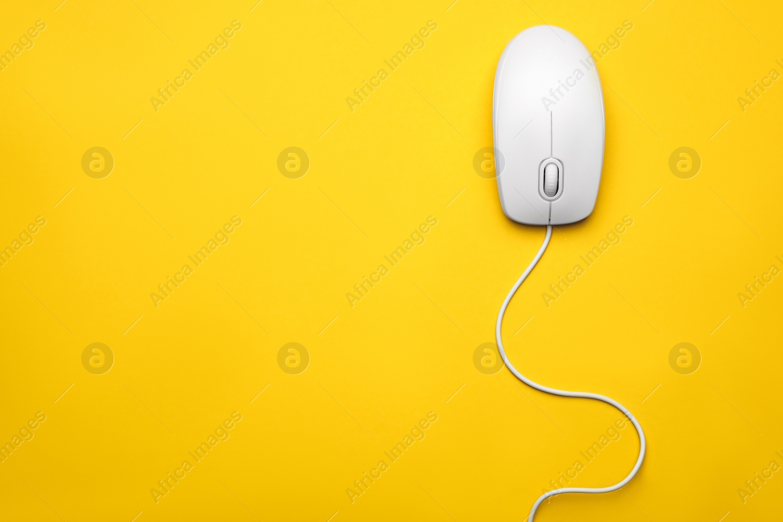 Photo of Wired computer mouse on yellow background, top view. Space for text