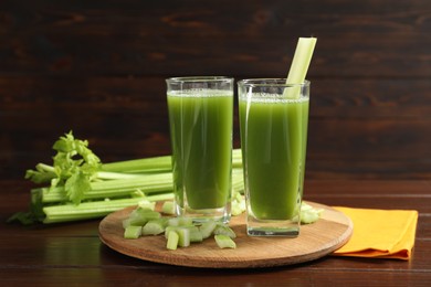 Photo of Glasses of delicious celery juice and vegetables on wooden table
