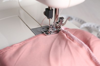 Photo of Sewing machine with color fabric on table, closeup