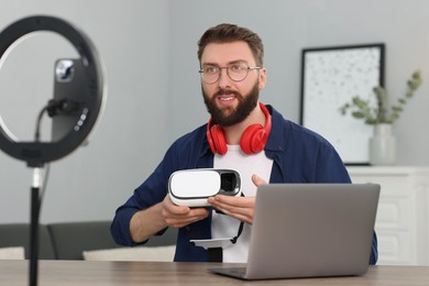 Technology blogger recording video review about virtual reality headset at home